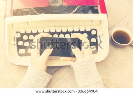Girl with cell phone and typewriter, vintage photo effect