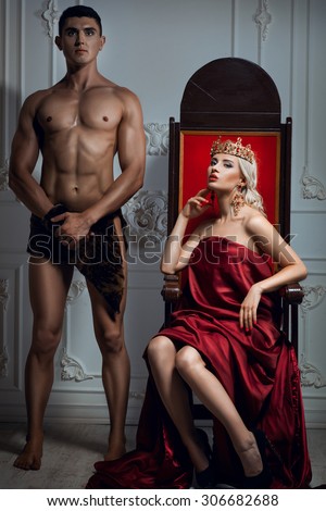 Queen sitting on a throne. Nearby is an athletic slave Royalty-Free Stock Photo #306682688