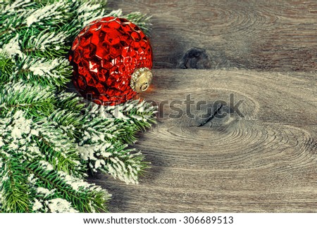 Decoration red christmas ball with pine branches over rustic wooden background. Retro style toned picture