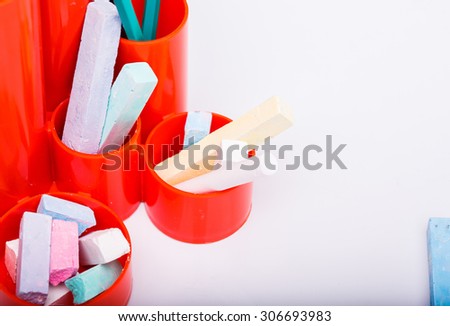 Colorful pencils of red yellow orange violet purple pink green and blue in stationary cup chalk and white sheet of paper on school background copyspace, horizontal picture