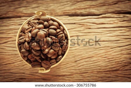Roasted coffee beans in the bucket on wooden background vintage style soft focus.