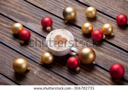 Cup of coffee and christmas bubbles on wooden background.