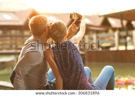 couple in love sitting in the park at sunset makes the selfie
