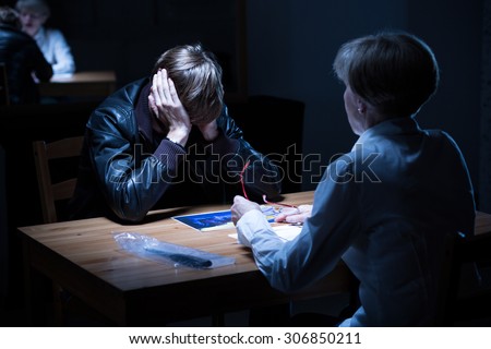 Young offender covering ears during police interrogation Royalty-Free Stock Photo #306850211