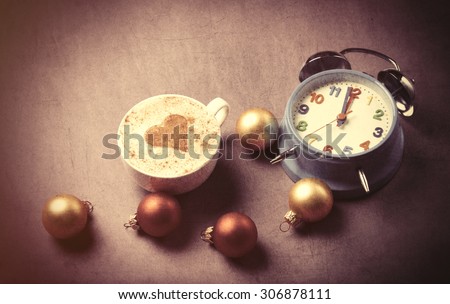 Cup of coffee with heart shape near alarm clock and christmas bubbles. Photo in old color image style.