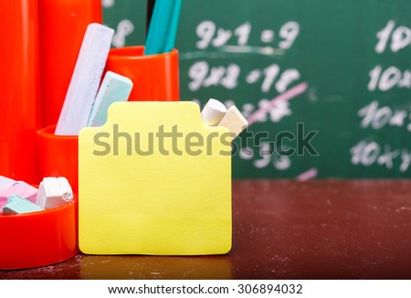 Colorful pencils of red yellow orange violet purple pink green and blue in stationary cup and stick on brown school desk on written with white chalk blackboard background copyspace, horizontal picture