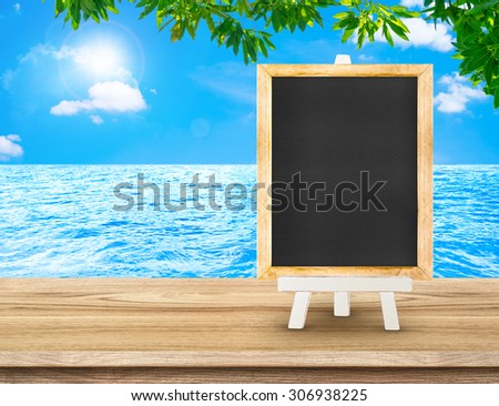 Blackboard menu with easel on wood table at sea with tree and sun burst, Copy space for adding your content
