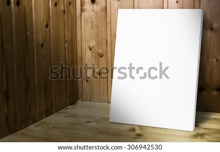 Blank white poster leaning at wooden wall in dark plank wood room,Mock up for adding your content.