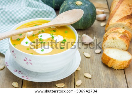 Pumpkin soup with sour cream on a wooden table