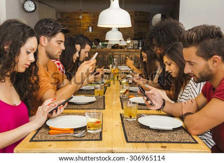 Group of friends at a restaurant with all people on the table occupied with cellphones Royalty-Free Stock Photo #306965114