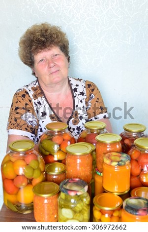 Mature housewife with home canned vegetables in the room