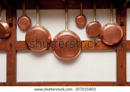 Row of vintage copper pans, different size, hung on wooden shelf in kitchen, vertical frame Royalty-Free Stock Photo #307035803