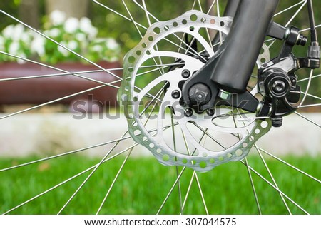 Disc brake detail on bicycle with grass in background.