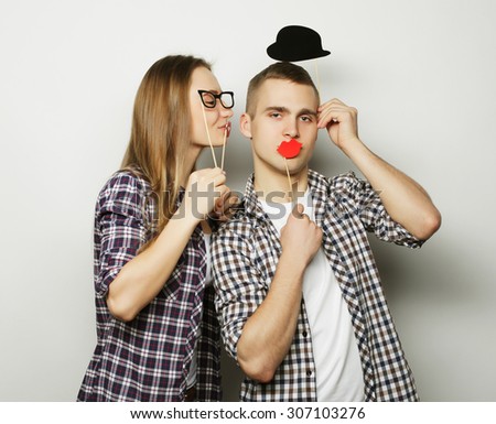 people, party, love and leisure concept - lovely couple holding party glasses and mustaches on sticks, over white  background