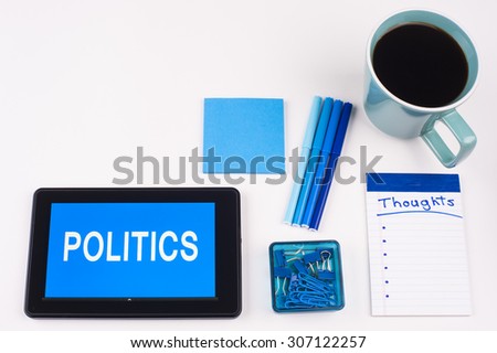 Business Term / Business Phrase on Tablet PC - Blues, cup of coffee, Pens, paper clips Calculator with a blue note pad on White - White Word(s) on blue - Politics