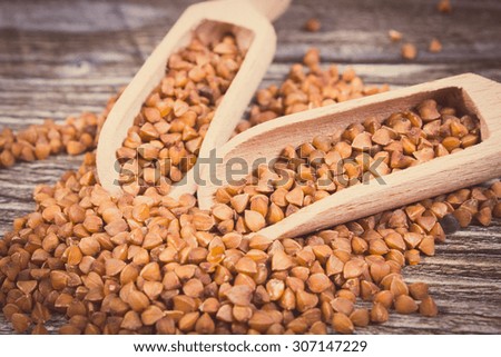 Vintage photo, Heap of uncooked brown buckwheat groats with spoon on wooden table, concept for healthy eating and nutrition