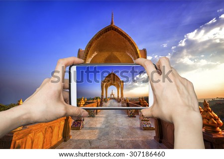 Girl taking pictures on mobile smart phone in Pagoda temple golden in thailand