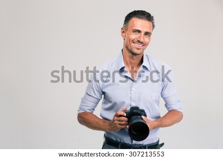 Portrait of a smiling photographer holding camera isolated on a white background