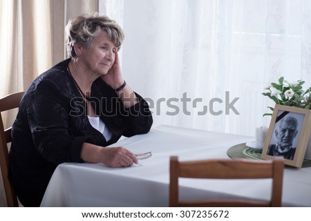Senior woman looking at dead husband's picture Royalty-Free Stock Photo #307235672