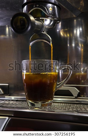 pouring simple espresso in glass of hot water for americano coffee
