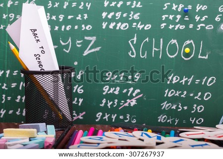 Colorful pencils and paper plane with back to school text written with white chalk blackboard on math