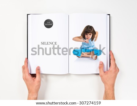 Girl making silence gesture printed on book