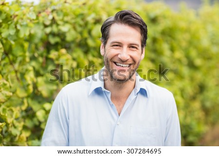 Young happy man smiling at camera in the grape fields Royalty-Free Stock Photo #307284695