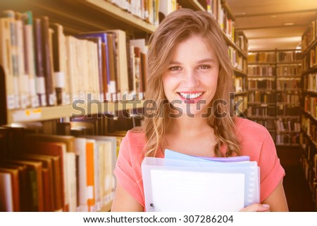 Smiling hipster holding notebook against close up of a bookshelf