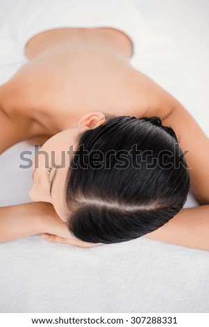 Pretty brunette enjoying a massage smiling at camera at the health spa