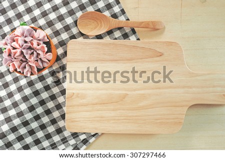 Sweet cupcake and wooden board on vintage tablecloth background. Toned image.