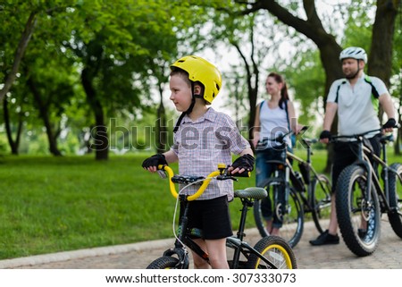 Happy family on their bike at the park on a sunny day. Focus on the child