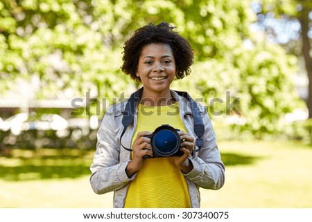 people, photography, technology, leisure and lifestyle - happy young african american female photographer with digital camera in summer park