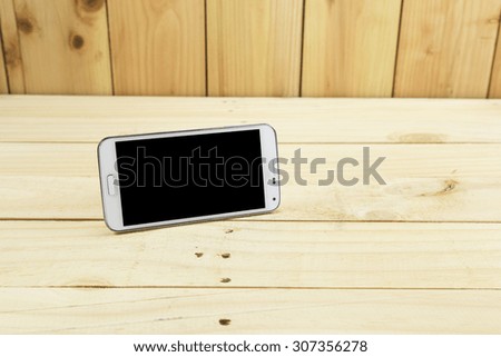 Smart phone with blank screen on wood board