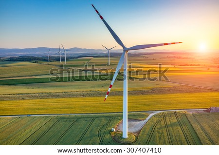 Beautiful sunset above the windmills on the field Royalty-Free Stock Photo #307407410