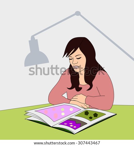  Young girl sitting at the table, watching in a picture book.
