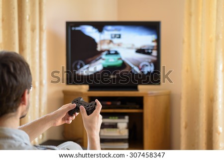 man playing racing video game on console (television) in home - stock photo
