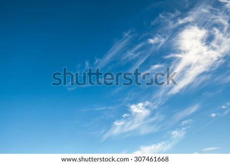 White cirrus clouds against a blue sky background