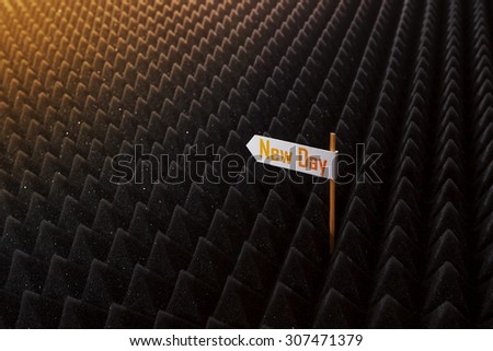 white directional sign saying NEW DAY on bumpy black background horizontal view