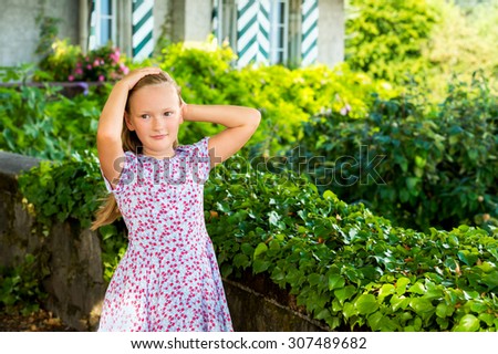Outdoor portrait of a cute little girl playing in a garden on a nice sunny day