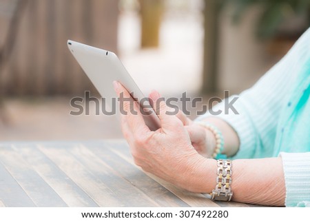 Close up shot of an elderly woman's hands operating a tablet computer