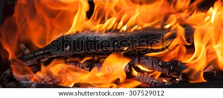 A close-up of intense red flames of fire. Soft focus. Focus put on the wooden base in the middle of picture.