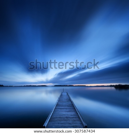 A small jetty on a lake near Amsterdam The Netherlands. A slow shutter speed was used to see the movement of the clouds in the sky. Photographed at dawn.