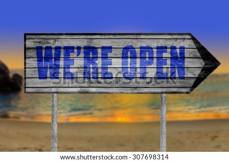We're open wooden sign with on a beach background