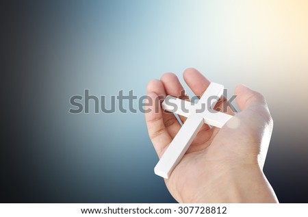 Hand and cross on dark light background , concept design