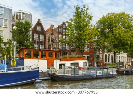 City view of Amsterdam canal and typical houses, boats and bicycles, Holland, Netherlands.