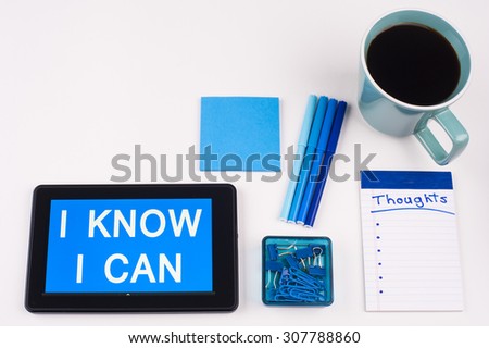 Business Term / Business Phrase on Tablet PC - Blue Colors, Coffee, Pens, Paper Clips and note pads on White - White Word(s) on blue - I Know I Can