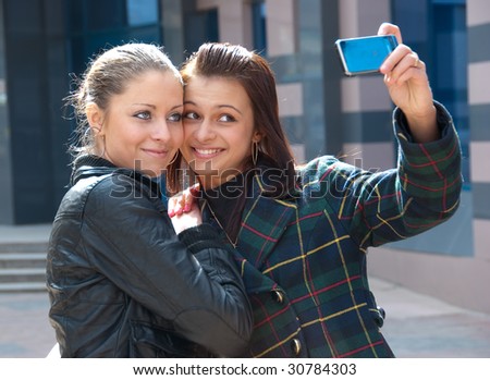 Two happy girls make self-portrait on a street