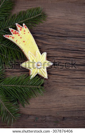 close-up still-life of fir branches and the gingerbread with pattern on magic Christmas holiday on background a wooden boards studio