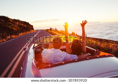 Driving into the Sunset. Romantic Young Couple Enjoying Sunset Drive in Classic Vintage Sports Car Royalty-Free Stock Photo #307893920