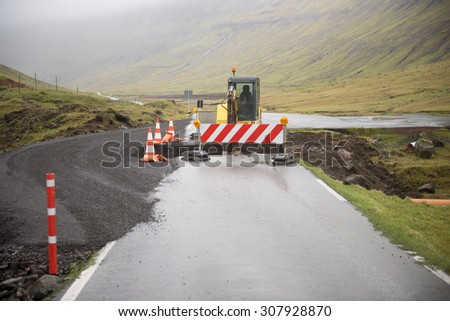 Road construction site on the Faroe Islands with road block sign and digger